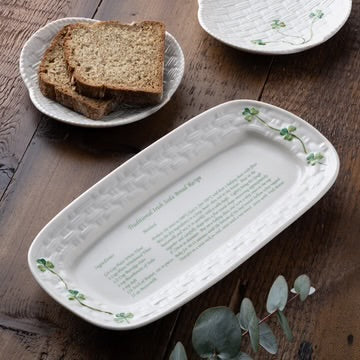 Rectangular ceramic platter with engraved text on a wooden surface with bread slices.