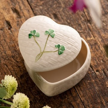 Heart-shaped white box with green leaf design on a wooden surface