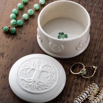 White jewelry box with intricate designs on a wooden surface with jewelry items.