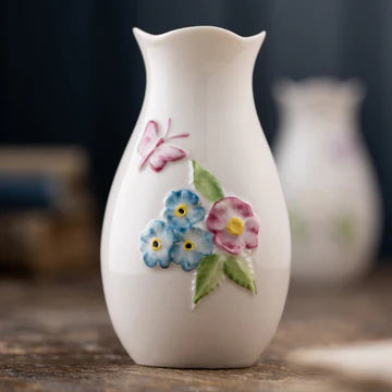 White ceramic vase with floral designs on a wooden surface