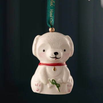 White dog-shaped ornament with a red collar and green ribbon on a dark background