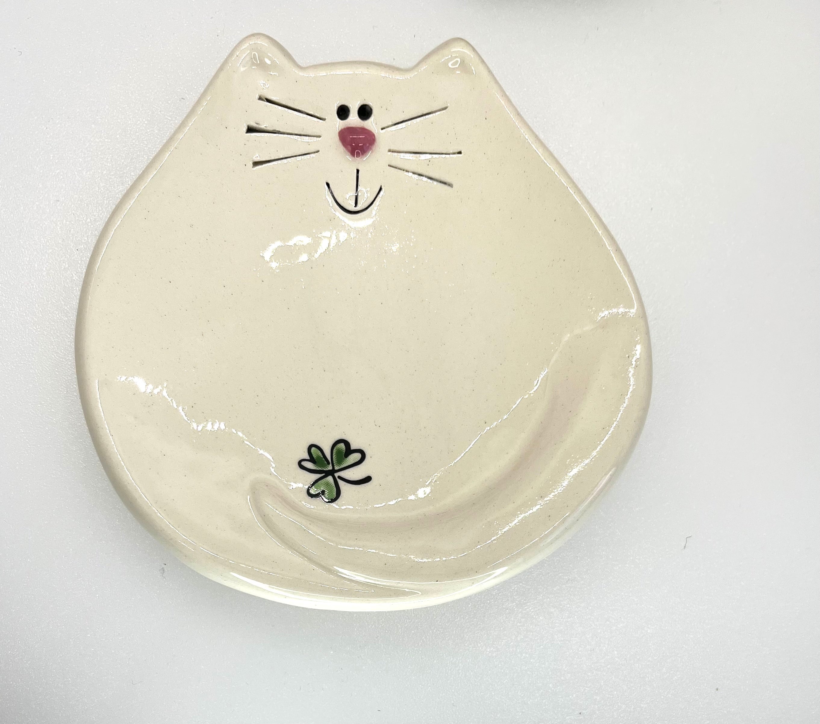 Ceramic dish shaped like a cat's face with a smile on a white background