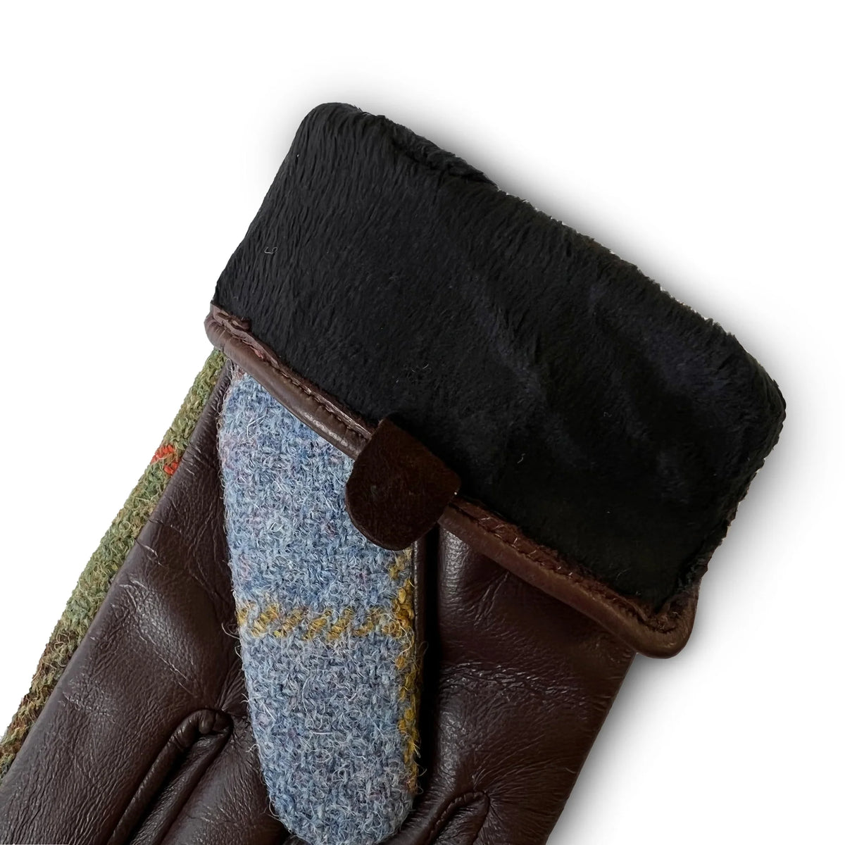 Close-up of a brown leather glove with black fur lining and blue fabric patch on a white background
