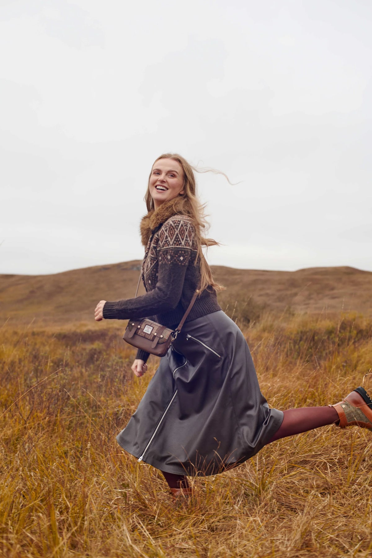 Woman running in a field with a brown bag