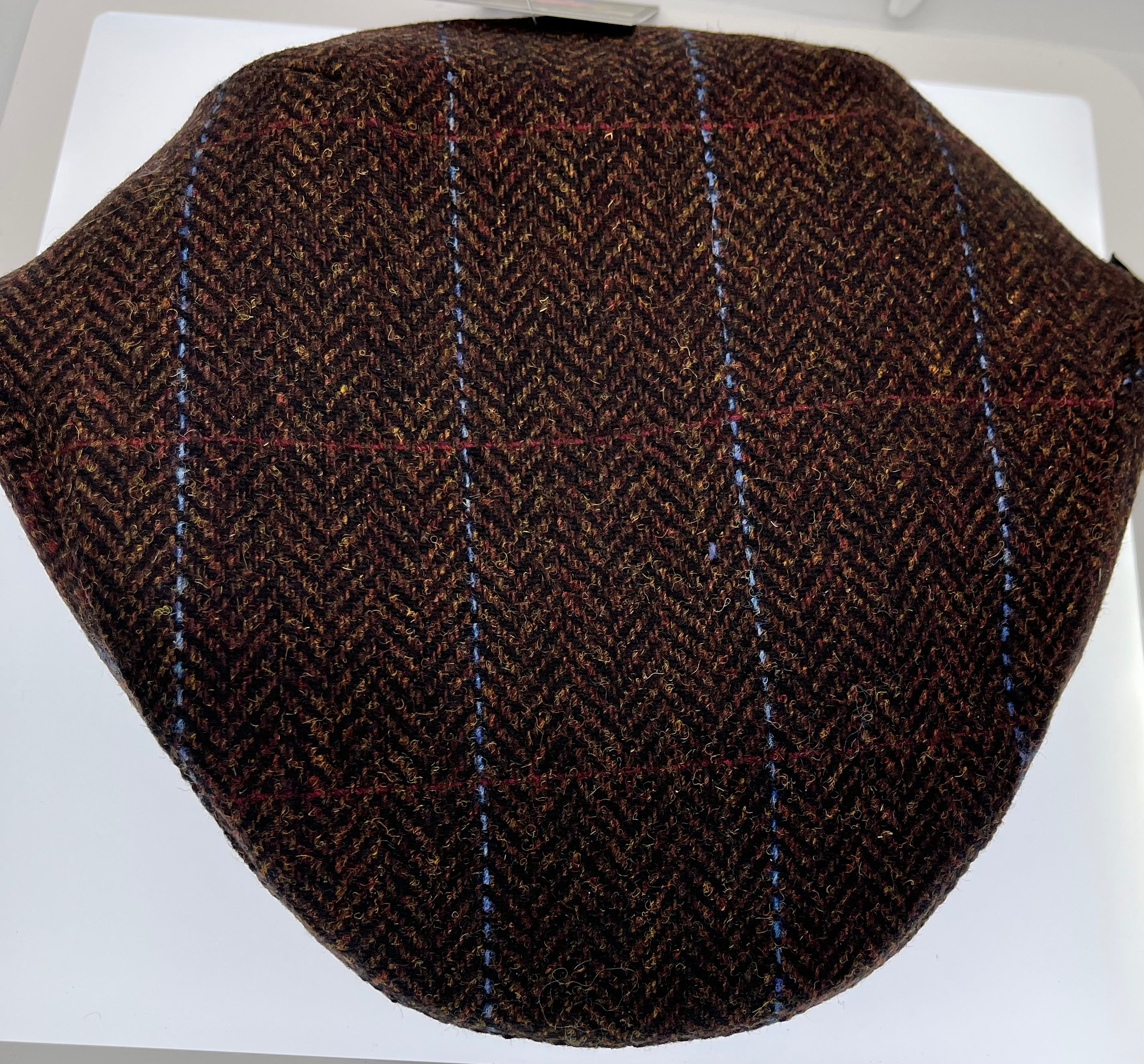 Brown tweed herringbone patterned flat cap on a white background