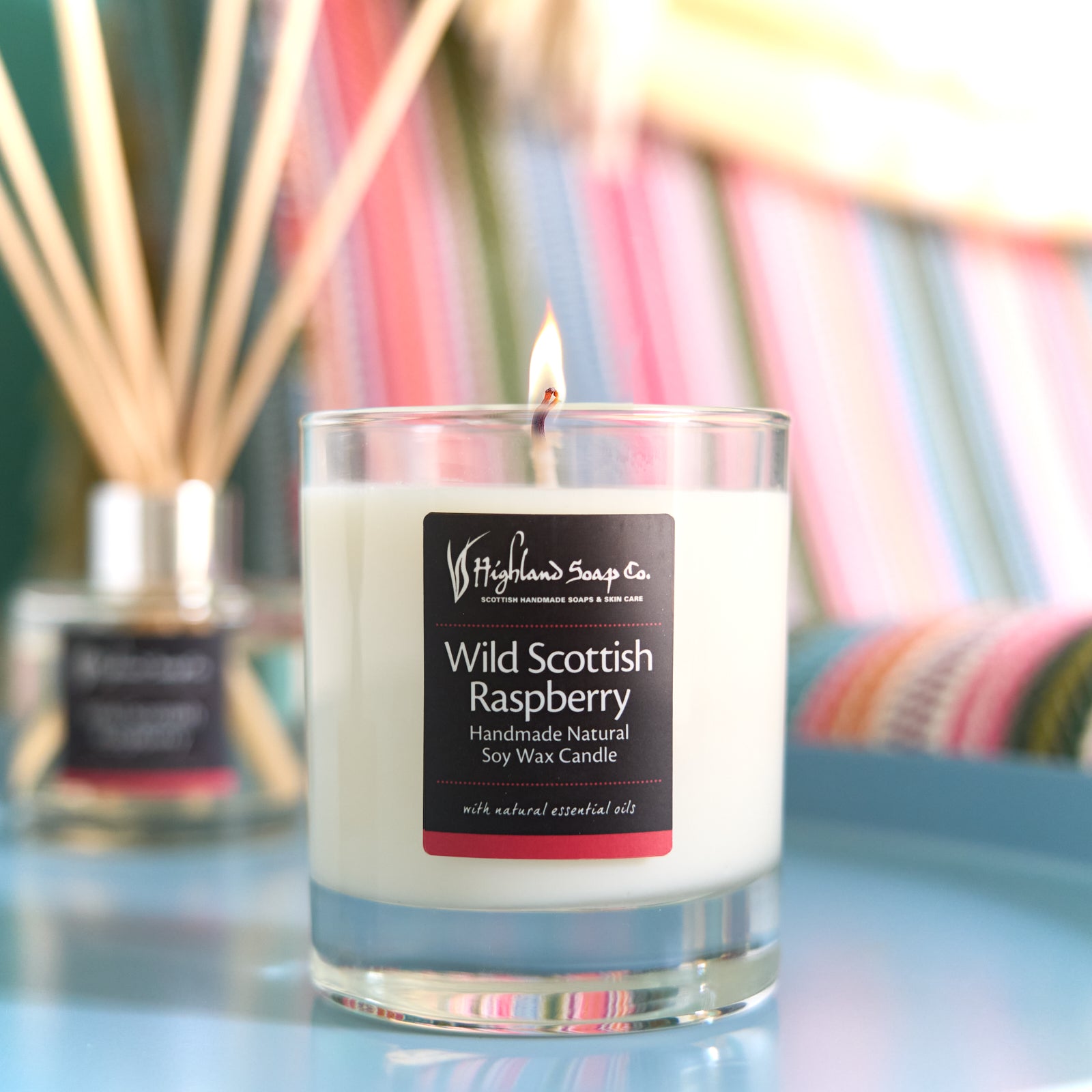 Candle labeled 'Wild Scottish Raspberry' by Highland Soap Co. with a blurred background