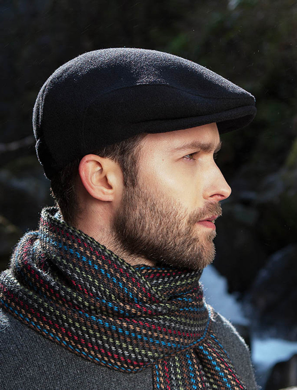 Man wearing a black flat cap and colorful scarf against a blurred natural background