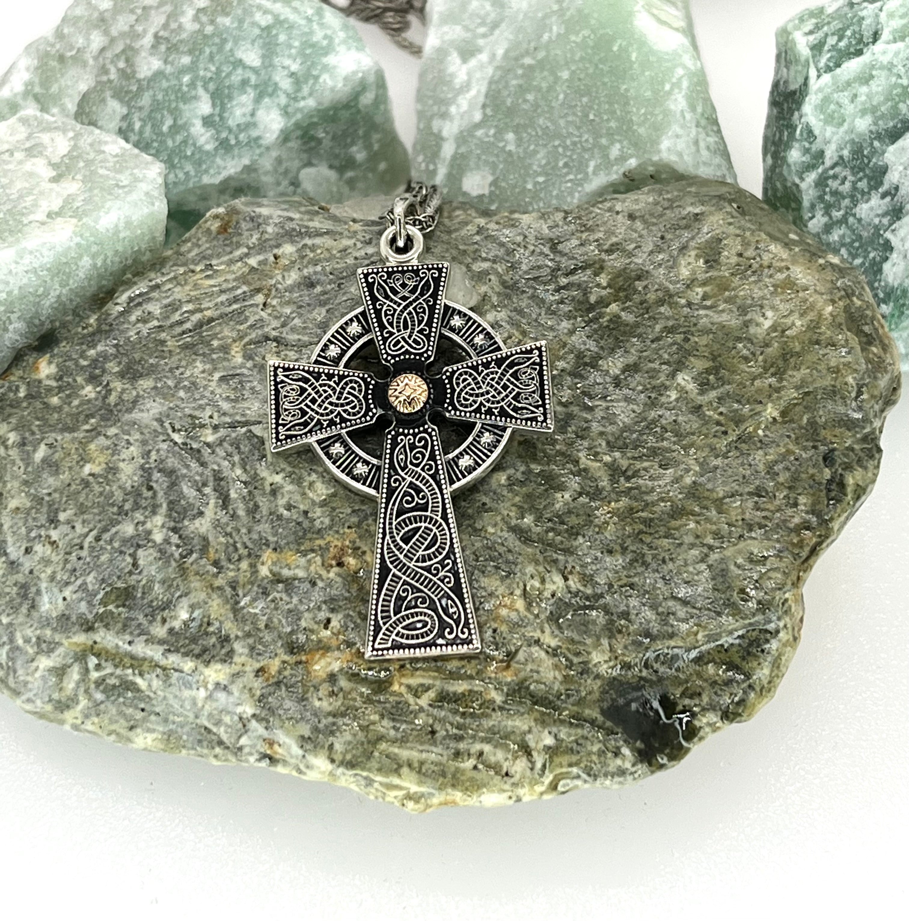 Silver Celtic cross pendant on a rock