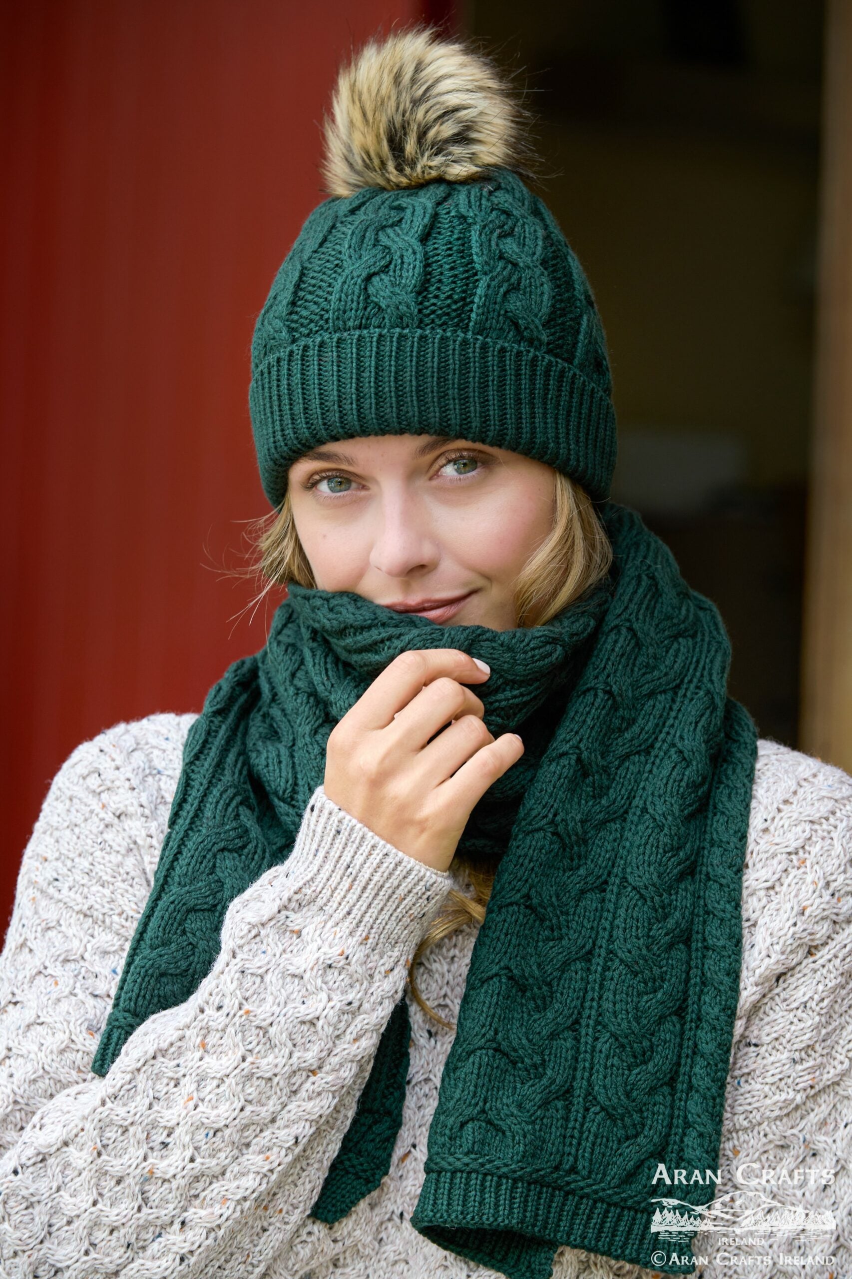 Person wearing a green knitted hat and scarf with a blurred background