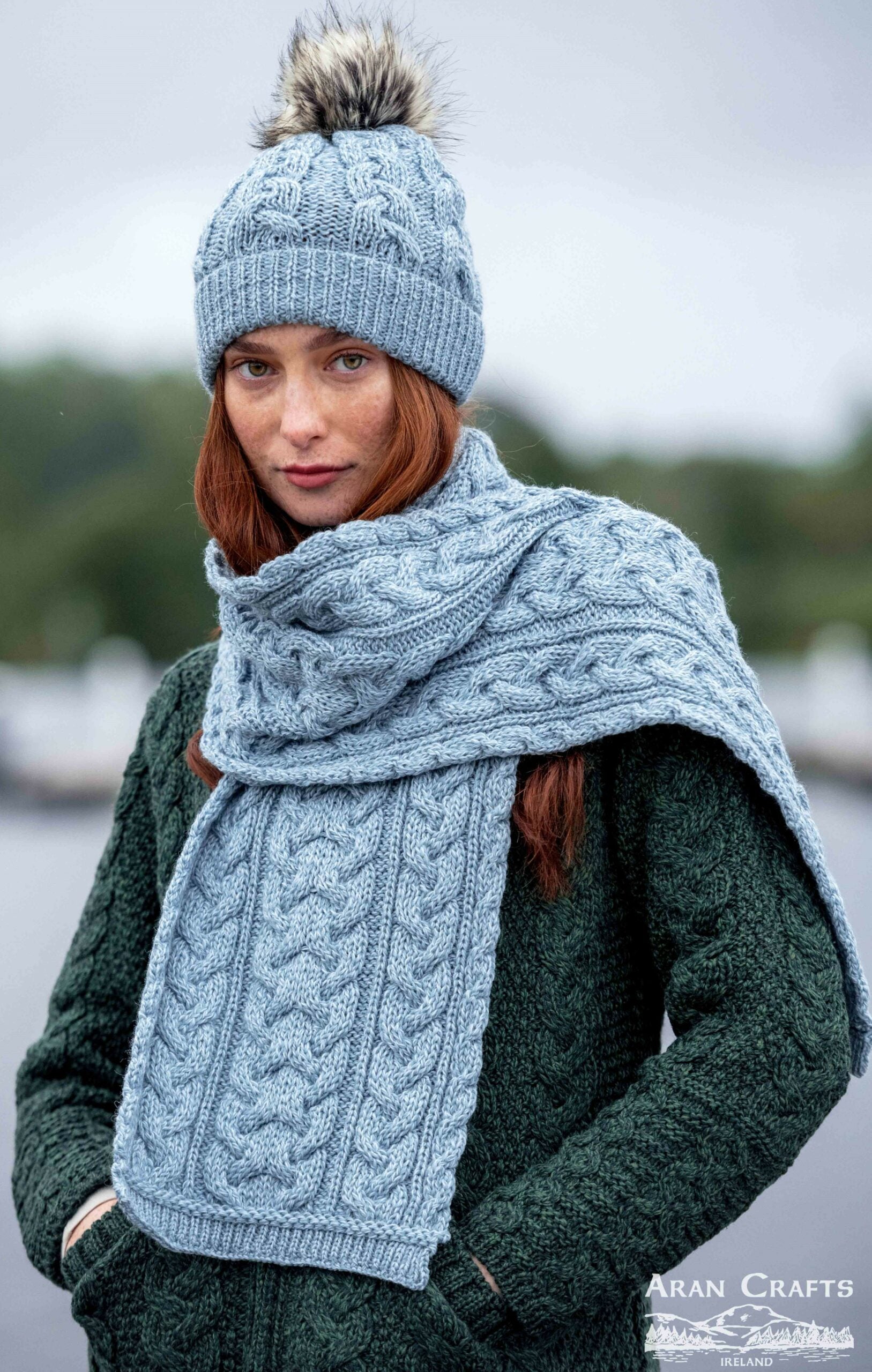 Person wearing a blue knitted hat and scarf with a blurred background