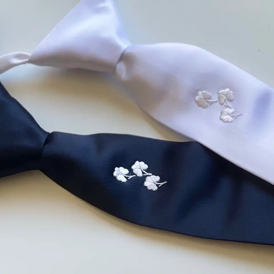 Navy blue tie with white floral embroidery on a white background