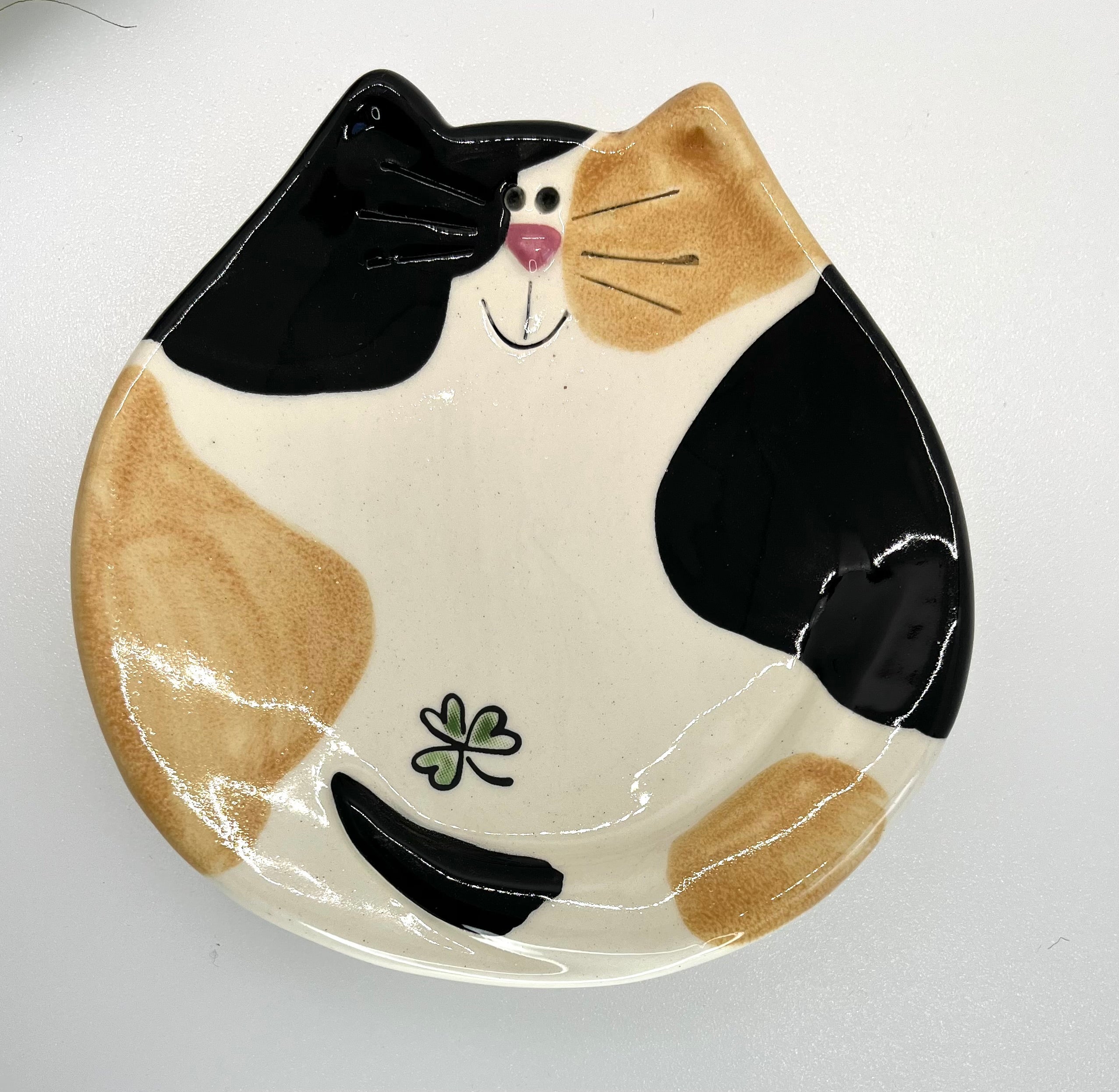 Ceramic plate shaped like a cat with black, brown, and white design on a white background