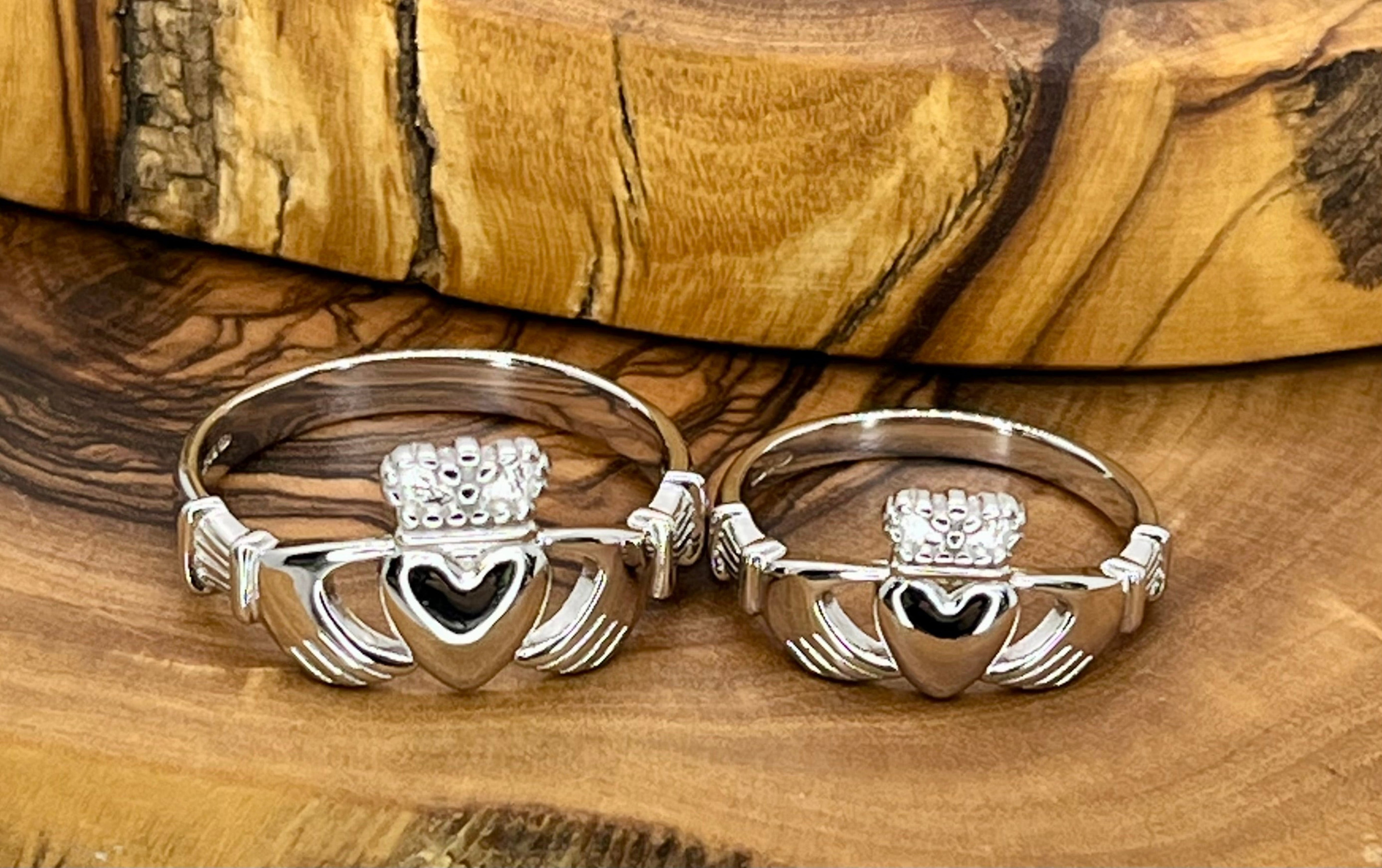 Two silver Claddagh rings on a wooden surface