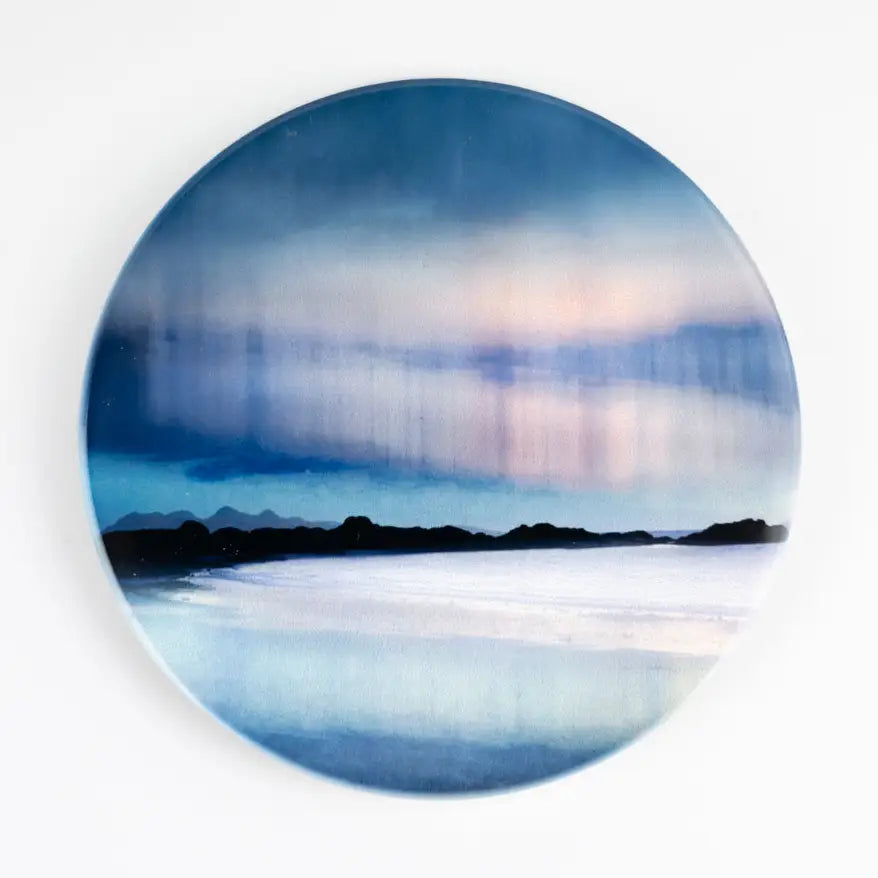 A round coaster featuring an abstract landscape painting of a blue and white seascape with a dark silhouette of mountains or land across the horizon, shown against a plain white background.