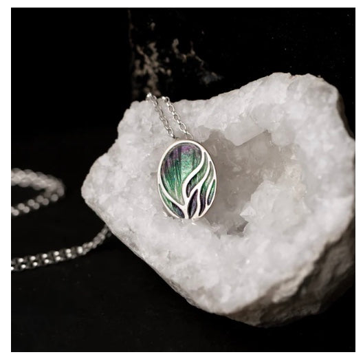 Silver necklace with a enameled green and purple pendant on a white crystal