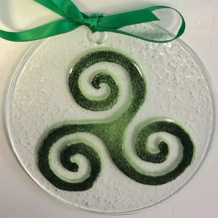 Decorative glass ornament with green and white spiral design on a white background