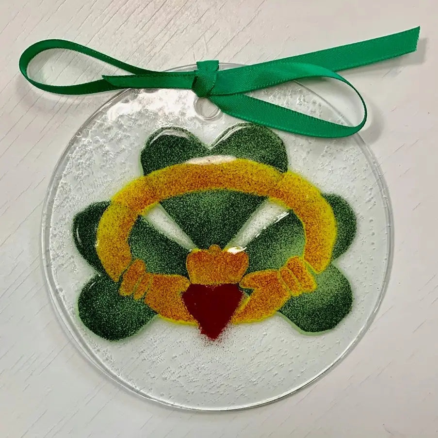 Decorative glass ornament with a Claddagh design on a white background