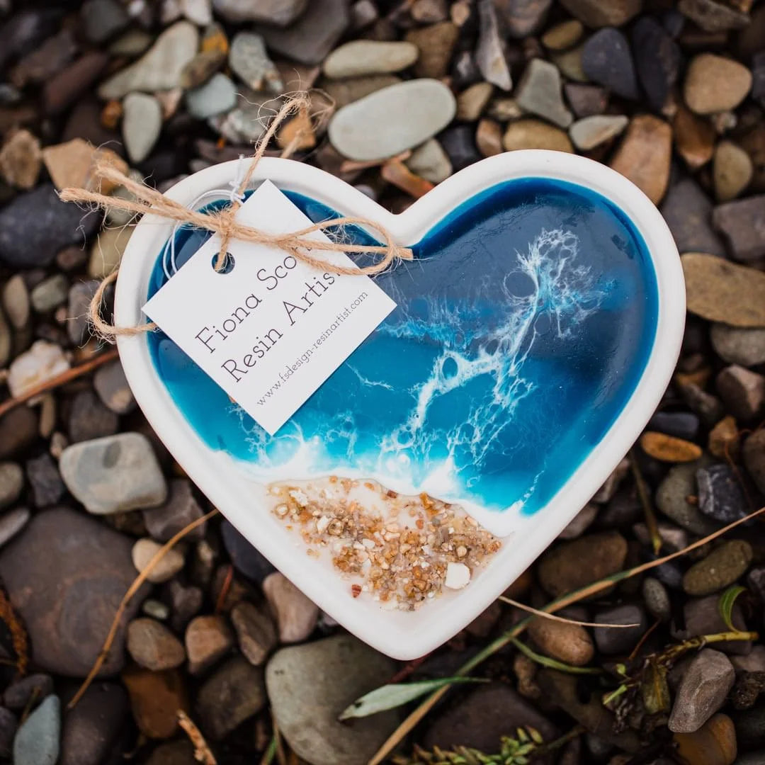 Heart-shaped resin art piece with blue and white design on pebbles