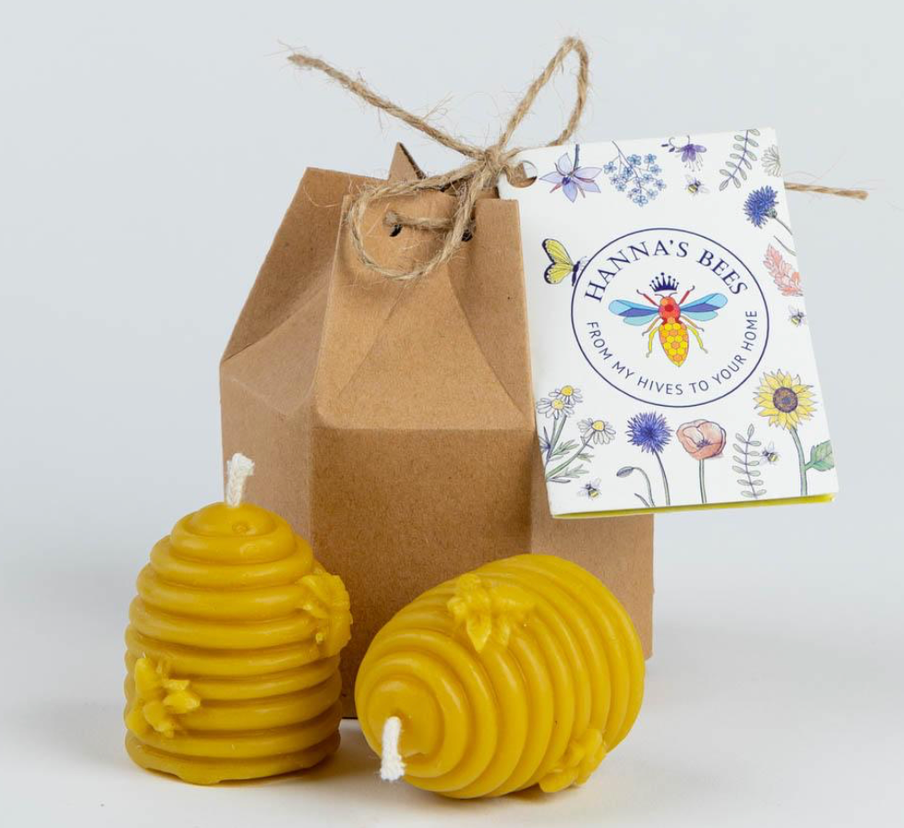 Two beehive-shaped candles with a brown box and 'Hanna's Bees' label on a white background.