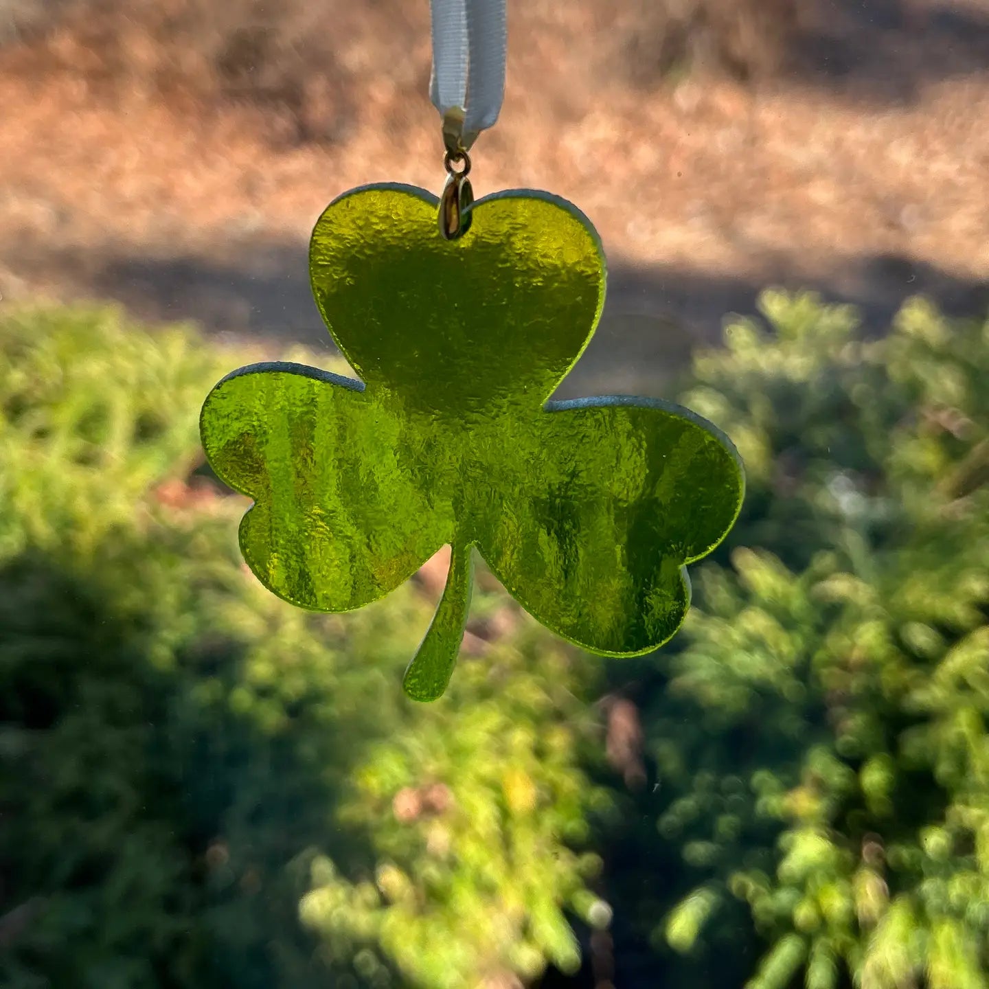 Green shamrock-shaped ornament on a blurred natural background