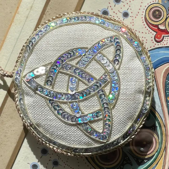 Round, embellished Irish linen ornament with intricate design on a textured surface