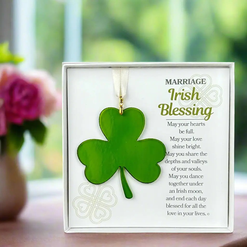 Green shamrock ornament with 'Irish Blessing' text on a white card, placed on a surface with a blurred floral background.