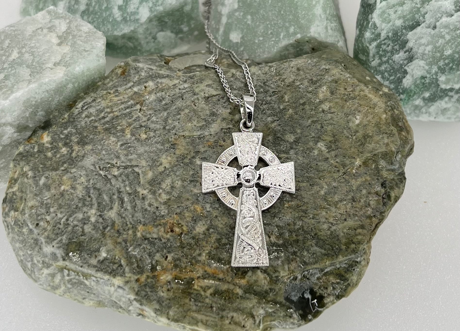 Silver Celtic cross necklace on a rock