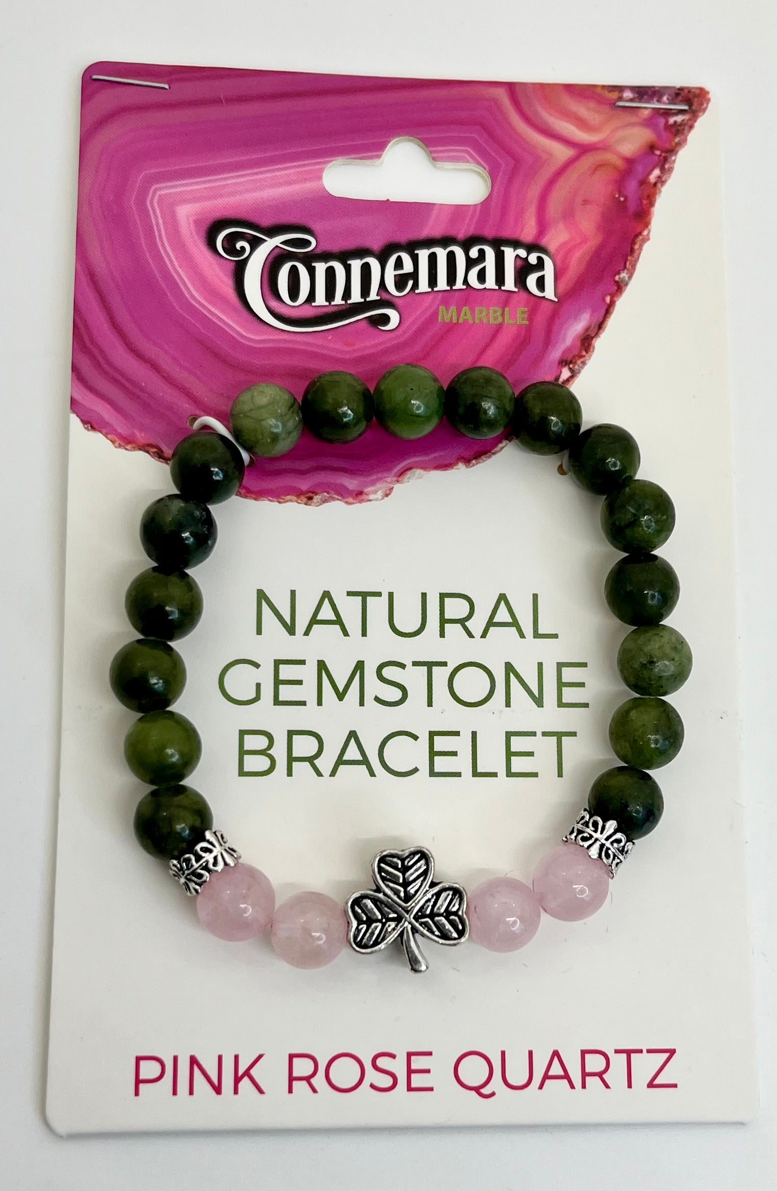 Green gemstone bracelet with pink rose quartz and a shamrock charm on Connemara packaging.