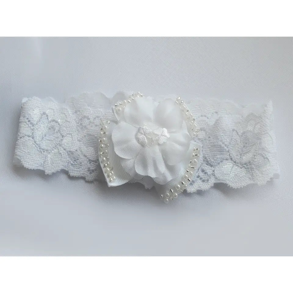 White lace baby headband with shamrock floral design on a light gray background