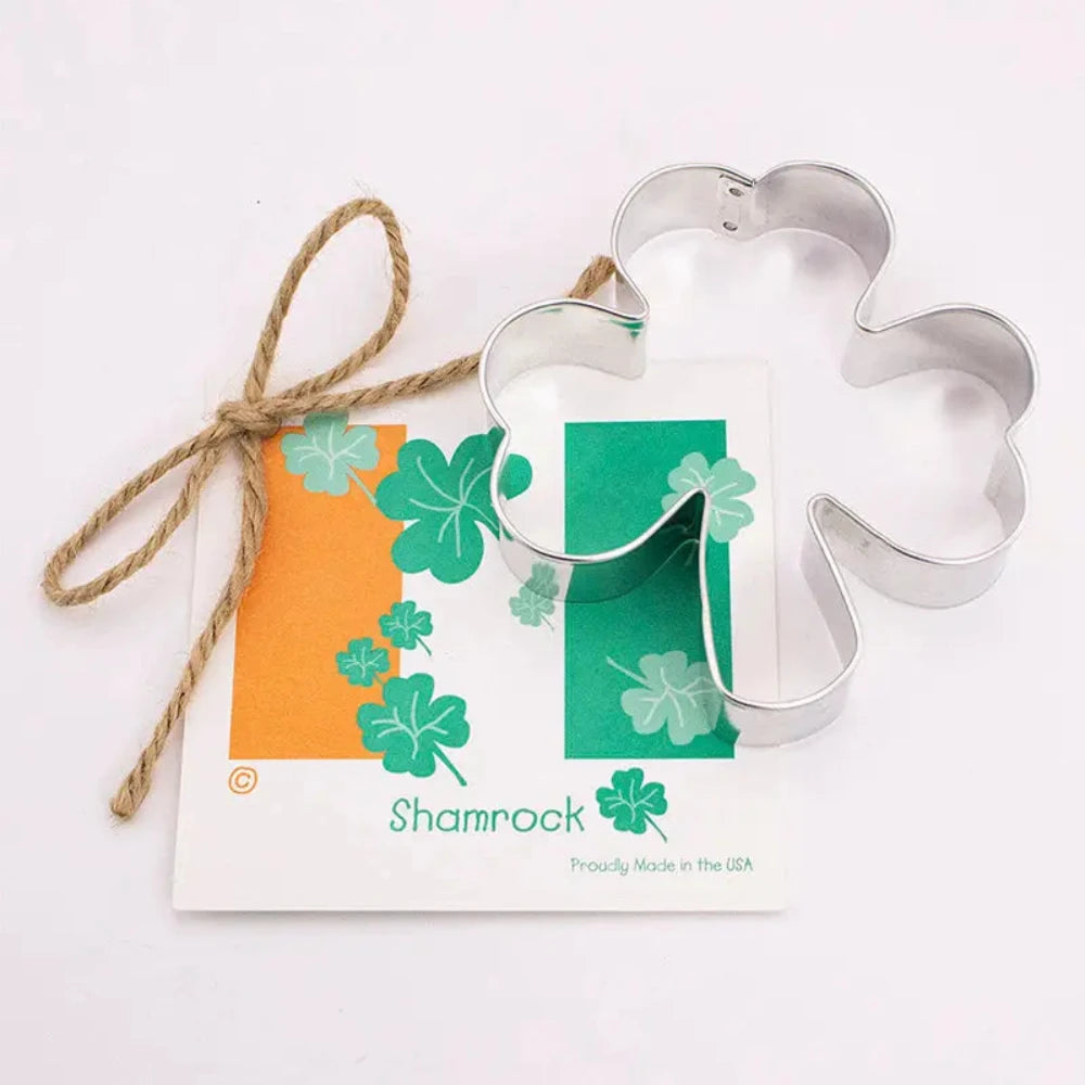 Metal shamrock cookie cutter with a shamrock-themed gift card on a white background