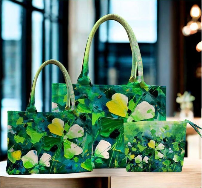 Set of three green handbags with floral design on a wooden surface.