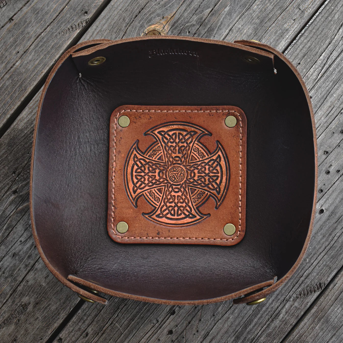 Brown leather tray with Celtic cross design on a wooden surface