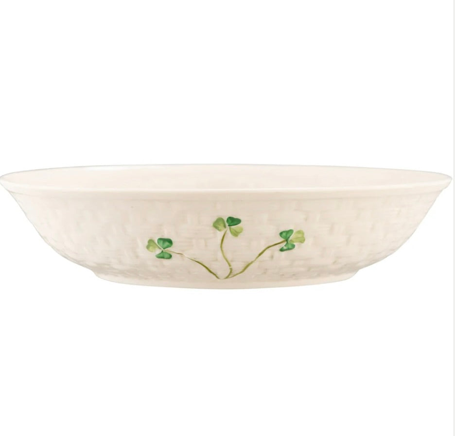 White pasta bowl with green shamrock floral design on a white background