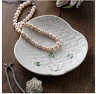 Pearl necklace on a decorative ceramic dish with floral design on a wooden surface