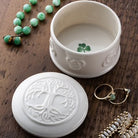 White jewelry box with intricate designs on a wooden surface with jewelry items.