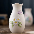 White ceramic vase with floral and butterfly design on a wooden surface