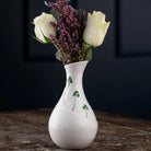 White vase with floral arrangement on a dark background