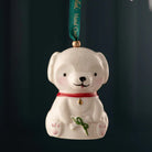 White dog-shaped ornament with a red collar and green ribbon on a dark background