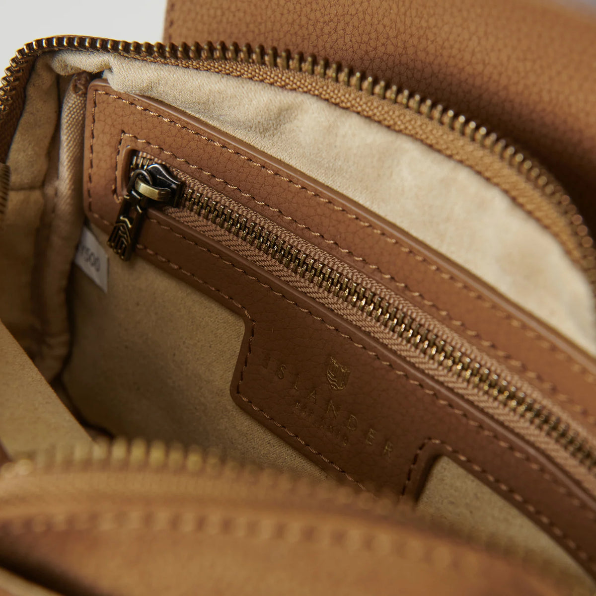 Close-up of a brown leather bag with a zipper, showing brand logo.