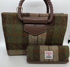 A small tweed handbag with braided brown handles and a matching zip pouch, both in a brown, green, and beige plaid pattern. The front of the bag has a brown leather tab embossed with 'ISLANDER tweed'.