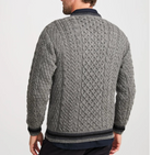 A man wearing a gray cable-knit sweater with dark navy ribbed trim, shown from the back against a plain light gray studio background.