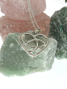 Silver heart-shaped pendant necklace on a rock with crystals in the background