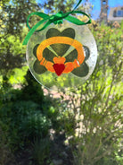 Decorative glass ornament with Celtic knot design hanging outdoors.