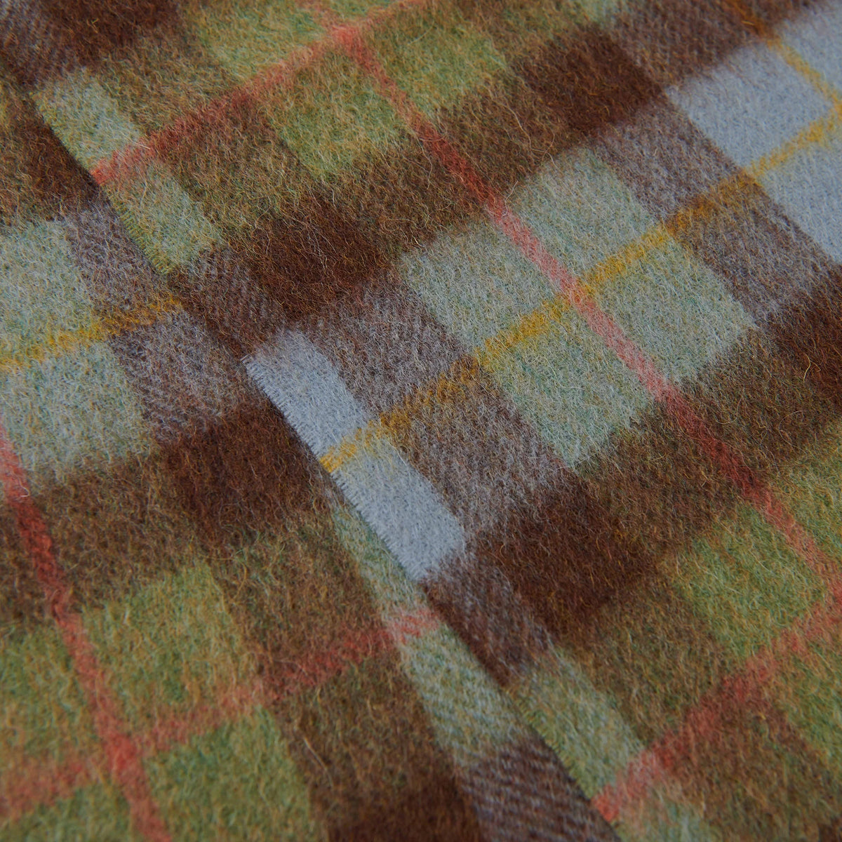 Close-up of a plaid fabric with brown, green, and red patterns.