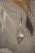 Silver pendant on a chain against a textured fabric background
