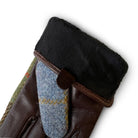 Close-up of a brown leather glove with black fur lining and blue fabric patch on a white background