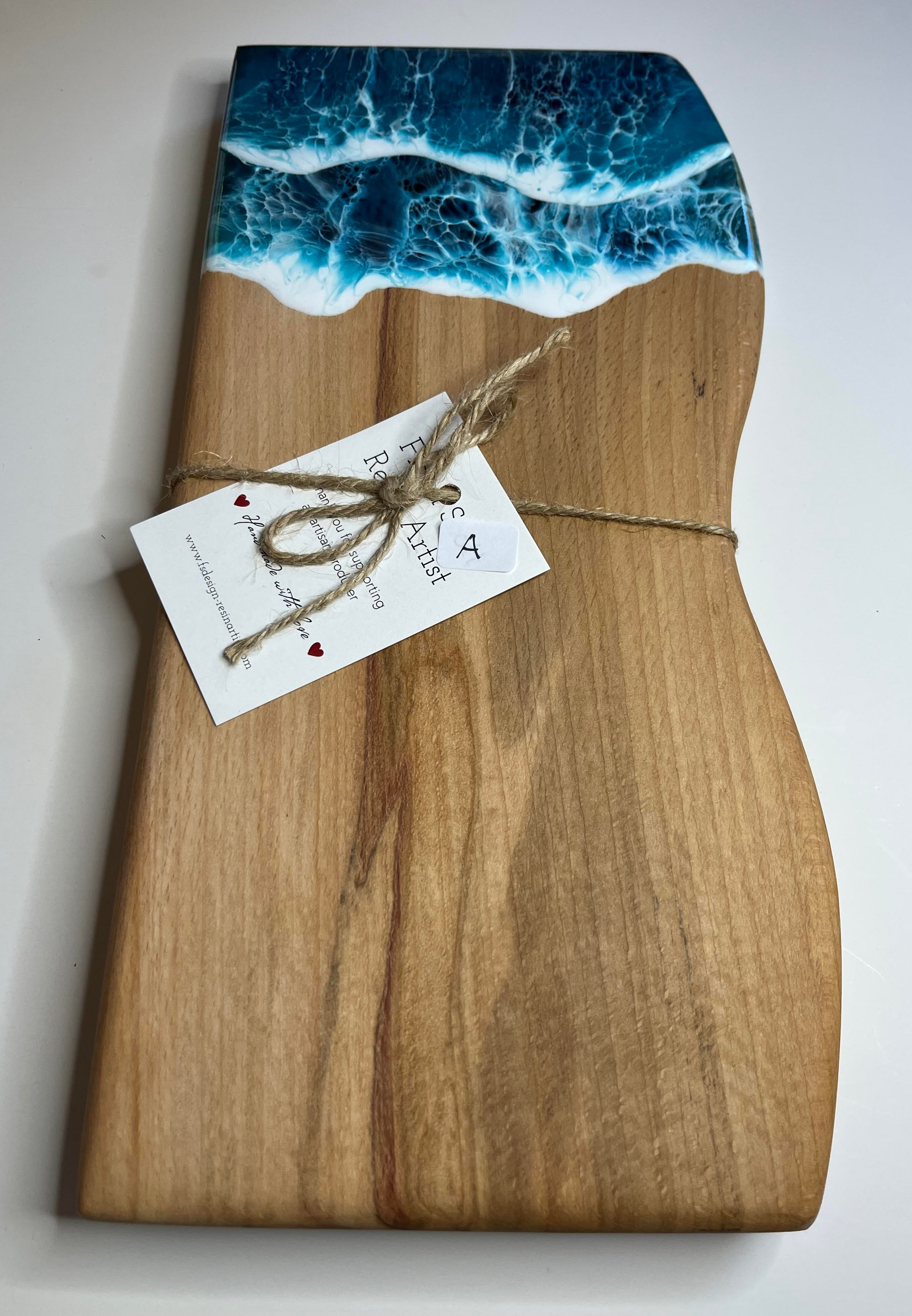 Wooden cutting board with ocean wave design and a tag on a white background