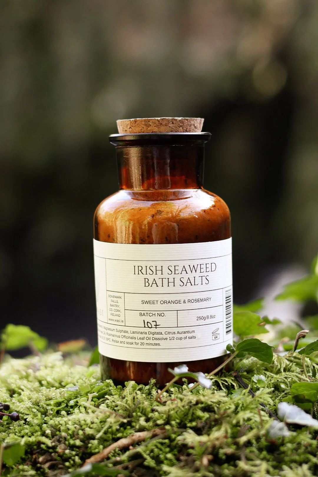 Bottle of Irish Seaweed Bath Salts on a mossy surface with a blurred natural background