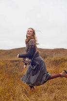 Woman running in a field with a brown bag