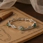 Silver bracelet with green stones on an old book
